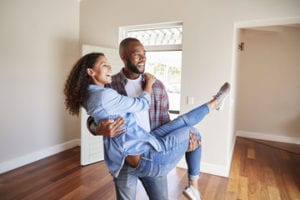 Happy couple embracing in their new home with hardwood floors