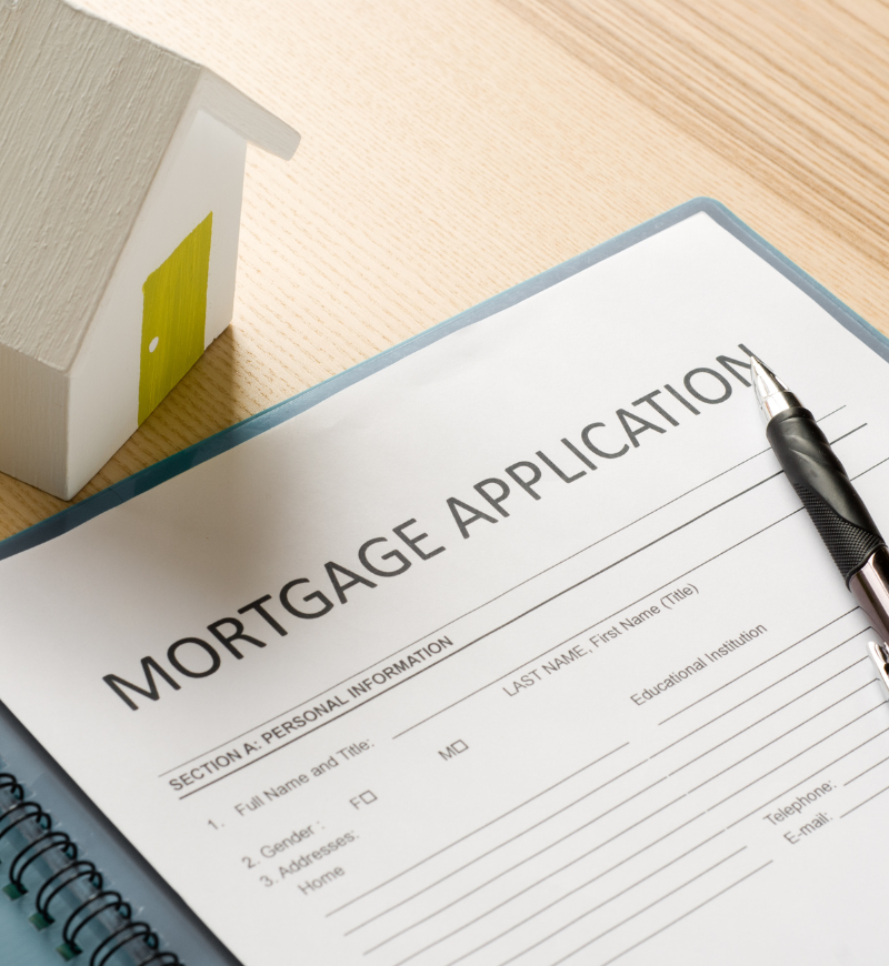 Mortgage application document with little wooden house model