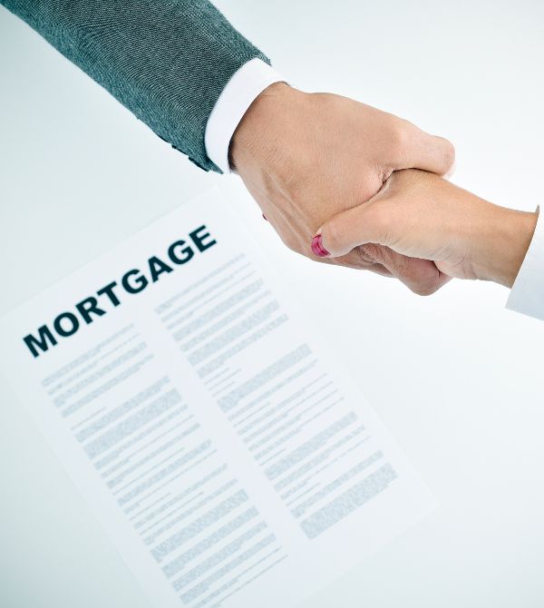 Two people shaking hands over a mortgage document