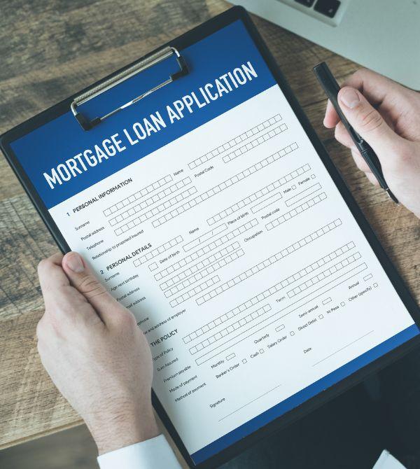 Person holding mortgage loan application document on clipboard