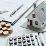 house model, money, pen and mortgage papers on table.