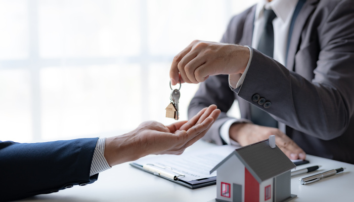 A professional mortgage lender is giving house keys to a client during a property sale transaction.