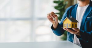 man holding house model - mortgage and loan concept