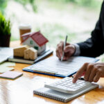 house model with business man signs a purchase contract or mortgage for a home, buy and sell home insurance concerning mortgage loan