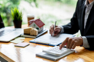 house model with business man signs a purchase contract or mortgage for a home, buy and sell home insurance concerning mortgage loan