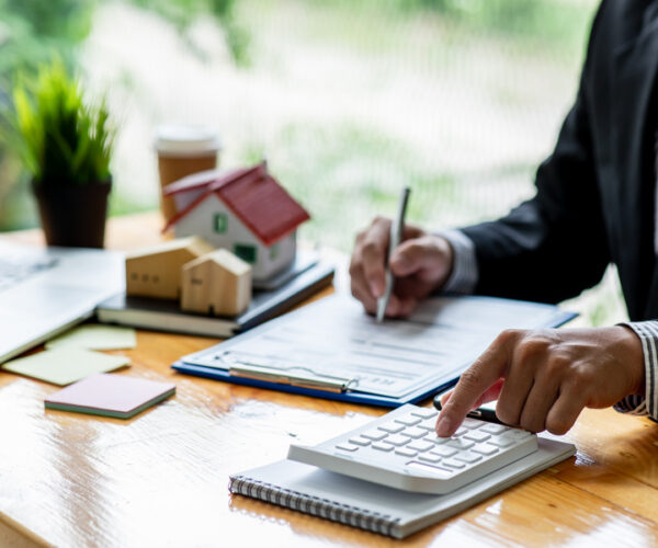 house model with business man signs a purchase contract or mortgage for a home, buy and sell home insurance concerning mortgage loan