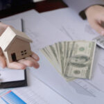 Real estate agent showing a miniature model house to the customer and using calculator. Concept for real estate investment and loan.