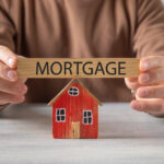Mortgage concept with a wooden house in the hands of a man