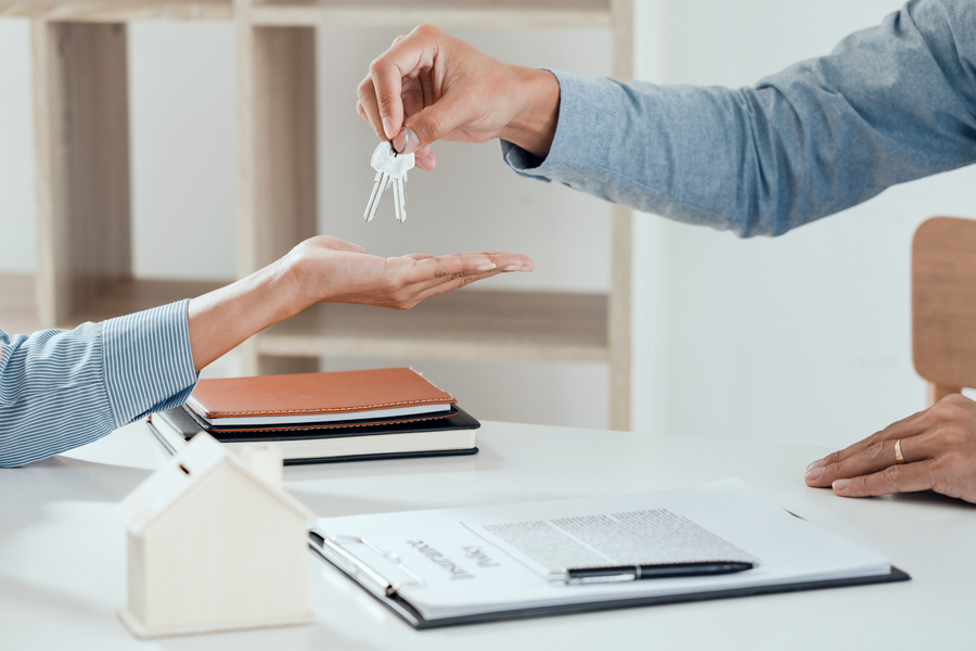 agent giving house keys to new buyer after signing agreement