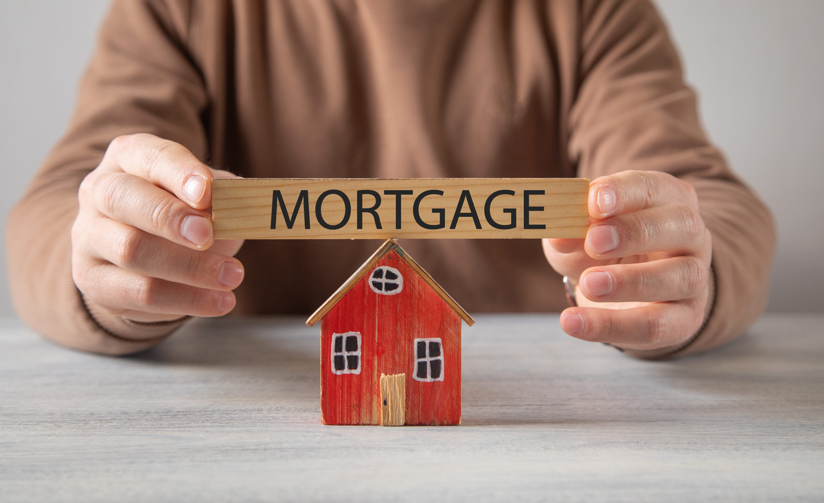 Mortgage concept with a wooden house in the hands of a man